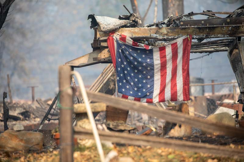 An American Flag hangs at the remains of a building destroyed by the Camp Fire.