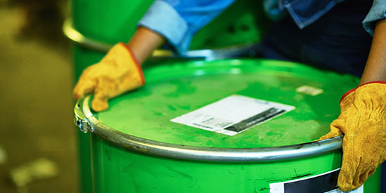 Photo of gloved hands lifting oil barrel