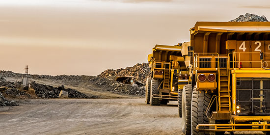 Photo of two haul trucks at a mining site