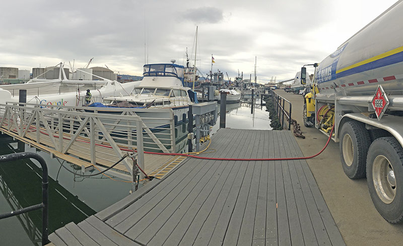 A photo of a Ramos Oil Company fuel truck providing over the water marine fueling to a Google Catamaran in California.