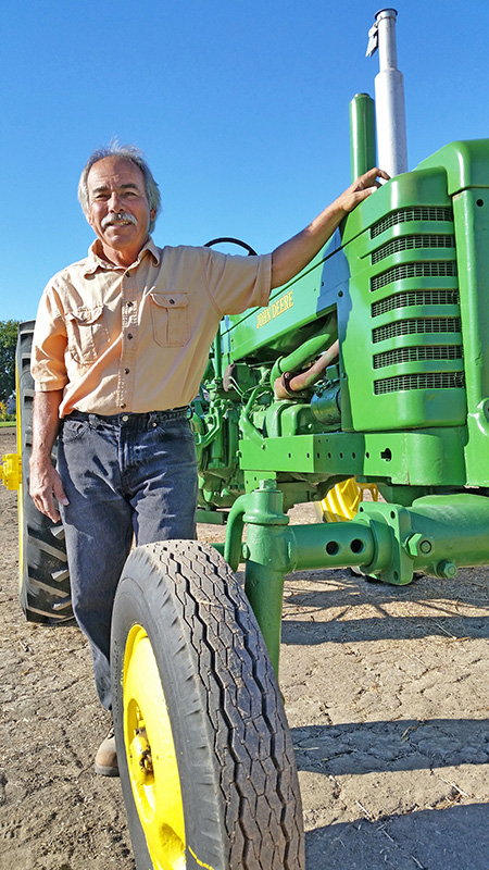 Photo of a man standing with a tractor.